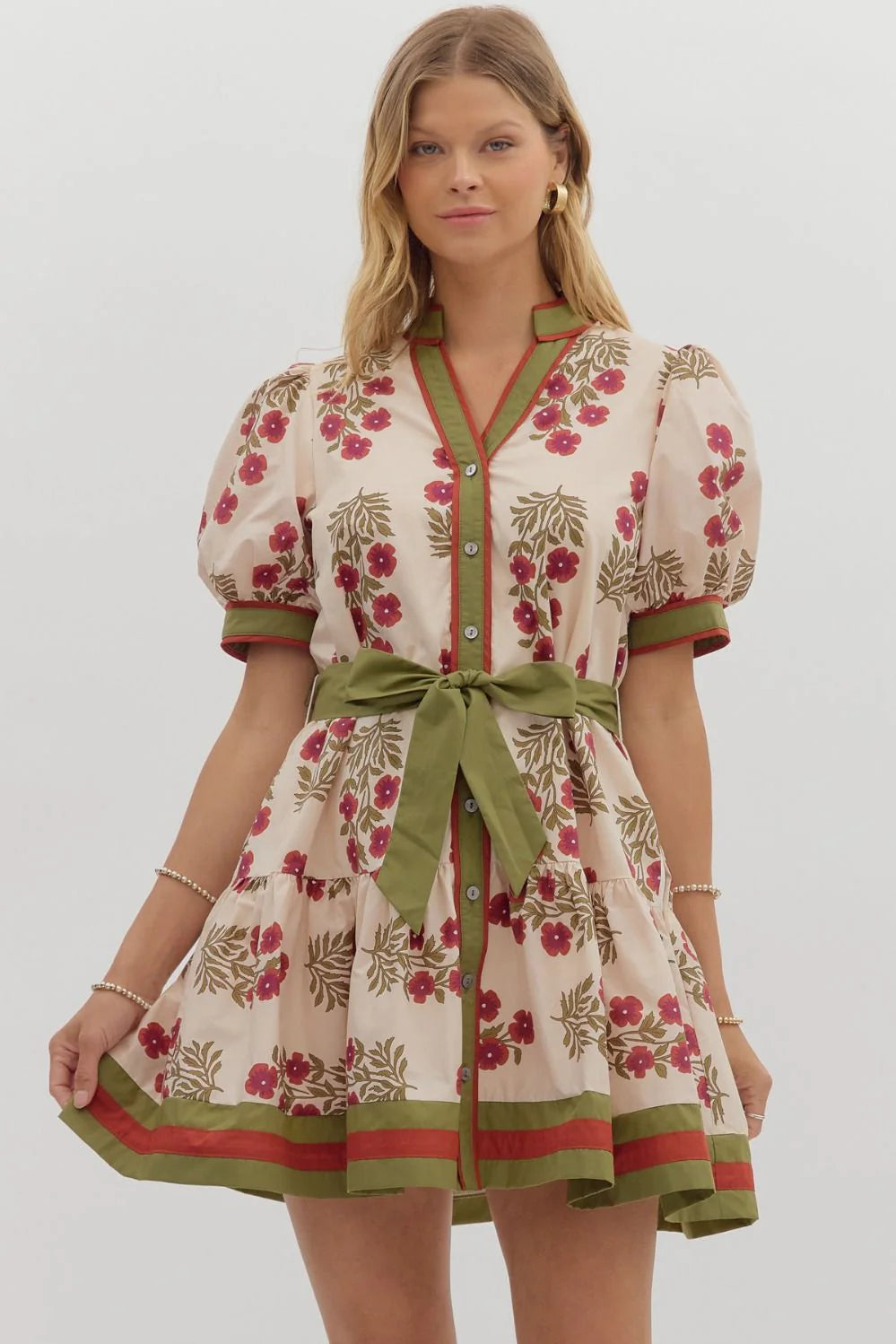 Woman wearing a floral dress with a green belt on a white background